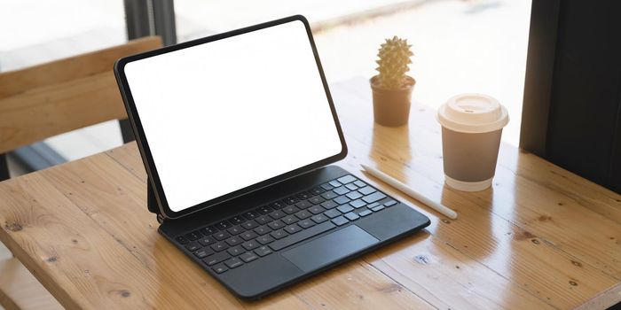 Mockup image of a black tablet with white blank screen on wooden desk
