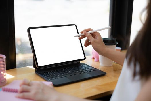 Mockup image of a woman hand using stylus with a black tablet with white blank screen on wooden desk