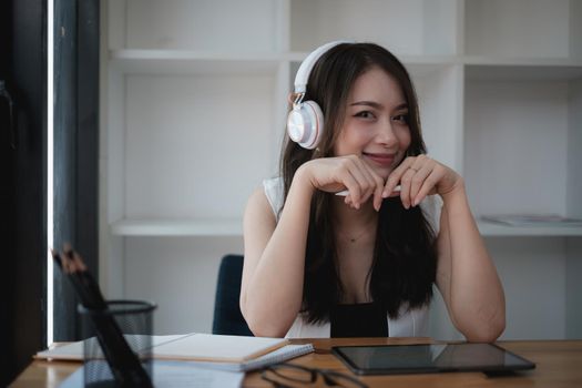 A joyful woman with headphones concentrates on a webinar on her laptop computer