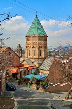 Photo conveying the atmosphere of the old district of Tbilisi. Cityscape of an old street with a cobblestone and a historical temple. Tbilisi, Georgia - 03.16.2021