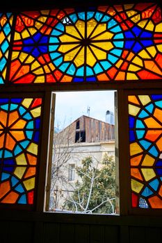 Authentic balcony of an old residential building with a stained glass window made of multicolored mosaics.