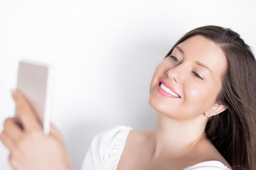 Happy smiling woman with smartphone having video call or taking selfie, portrait on white background. People, technology and communication concept.