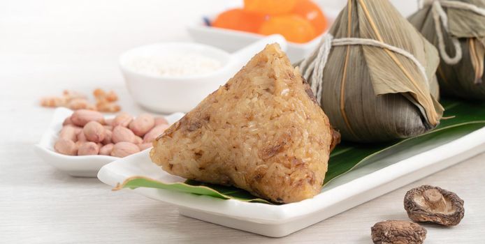 Zongzi. Rice dumpling for Chinese traditional Dragon Boat Festival (Duanwu Festival) on bright wooden table background with ingredient.