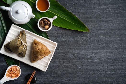 Zongzi. Rice dumpling top view design concept for Chinese traditional Dragon Boat Festival (Duanwu Festival) over dark black slate background.