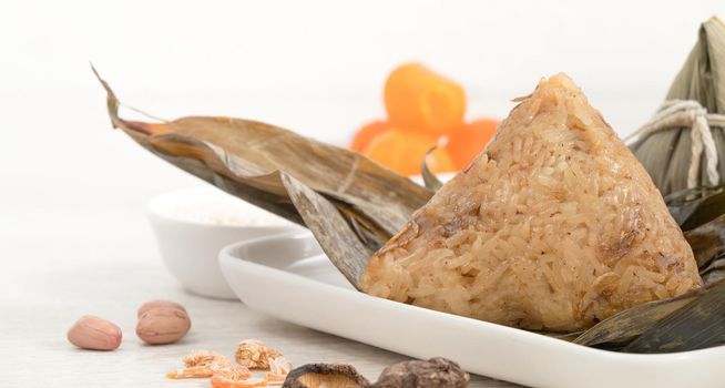 Zongzi. Rice dumpling for Chinese traditional Dragon Boat Festival (Duanwu Festival) on bright wooden table background with ingredient.