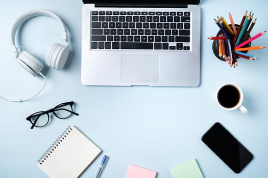 Online learning design concept. Top view of student table with computer, headphone and stationeries on blue table background.