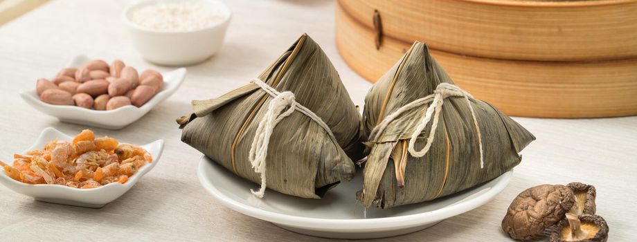 Zongzi. Rice dumpling for Chinese traditional Dragon Boat Festival (Duanwu Festival) on bright wooden table background with window.