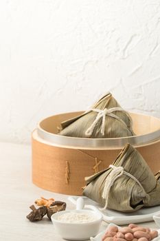 Zongzi. Rice dumpling for Chinese traditional Dragon Boat Festival (Duanwu Festival) on bright wooden table background with window.