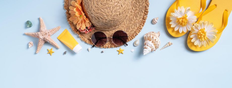 Summer beach background design concept. Top view of holiday travel with shells, hat, slipper on blue background.