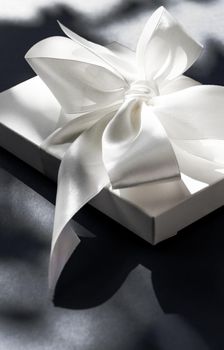 Anniversary celebration, shop sale promotion and luxe surprise concept - Luxury holiday white gift box with silk ribbon and bow on black background, luxe wedding or birthday present