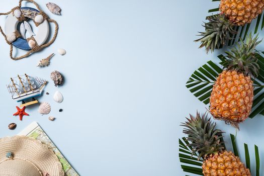 Summer fruit background design concept. Top view of holiday travel beach with shells, hat, pineapple and palm leaves on blue background.