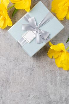 Mother's day background concept. Top view design of holiday greeting gift with yellow tulip bouquet on bright gray table background
