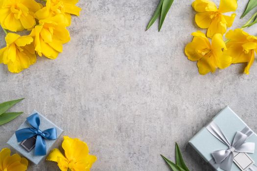 Mother's day background concept. Top view design of holiday greeting gift with yellow tulip bouquet on bright gray table background