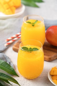 Fresh beautiful delicious mango juice. Close up design concept of smoothie cold drink in a glass cup with paper straw on gray table background.