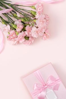 Mother's day background concept. Top view design of holiday greeting gift with carnation bouquet on bright pink table background