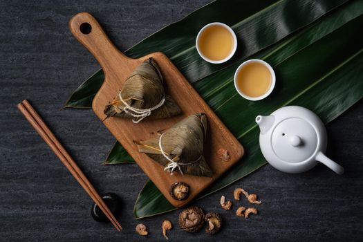 Zongzi. Rice dumpling top view design concept for Chinese traditional Dragon Boat Festival (Duanwu Festival) over dark black slate background.