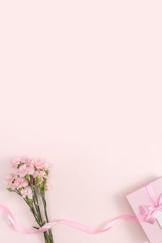 Mother's day background concept. Top view design of holiday greeting gift with carnation bouquet on bright pink table background