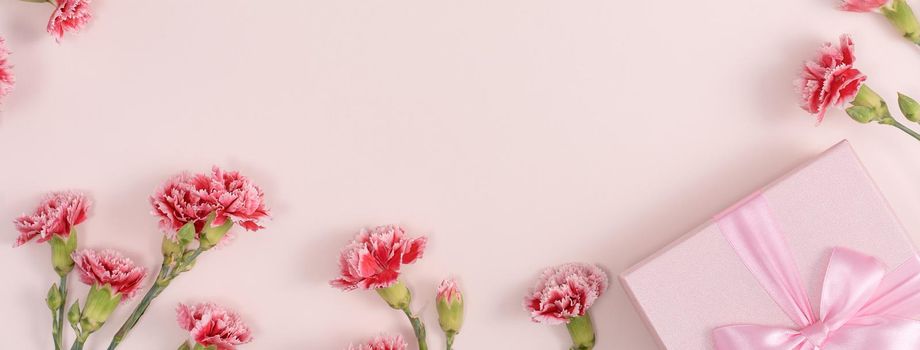 Mother's day background concept. Top view design of holiday greeting gift with carnation bouquet on bright pink table background