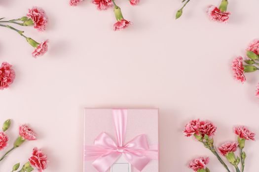 Mother's day background concept. Top view design of holiday greeting gift with carnation bouquet on bright pink table background