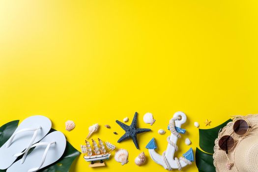 Summer beach design concept. Top view of holiday travel with shells, hat, slipper on yellow background.