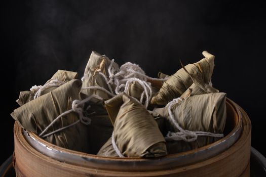 Zongzi rice dumpling for Chinese traditional Dragon Boat Festival (Duanwu Festival) over dark background.