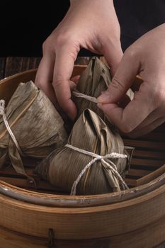 Zongzi rice dumpling for Chinese traditional Dragon Boat Festival (Duanwu Festival) over dark background.