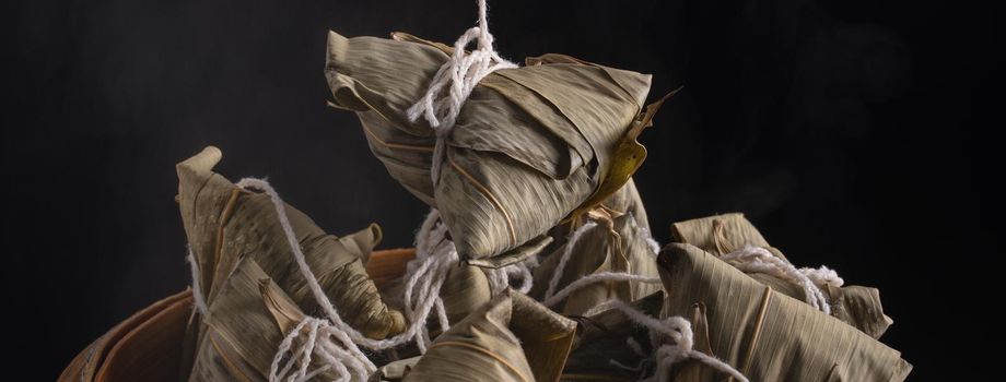 Zongzi rice dumpling for Chinese traditional Dragon Boat Festival (Duanwu Festival) over dark background.