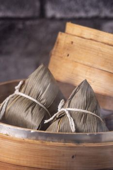 Zongzi rice dumpling for Chinese traditional Dragon Boat Festival (Duanwu Festival) over dark background.