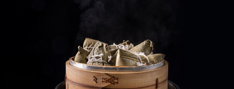 Zongzi rice dumpling for Chinese traditional Dragon Boat Festival (Duanwu Festival) over dark background.