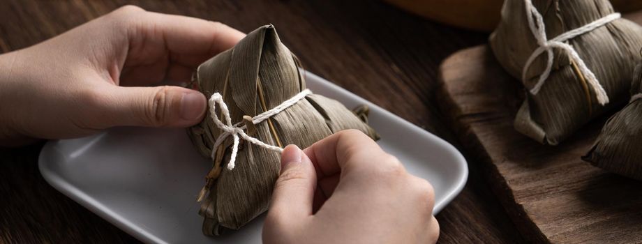 Eating Zongzi rice dumpling for Chinese traditional Dragon Boat Festival (Duanwu Festival) celebration event concept.