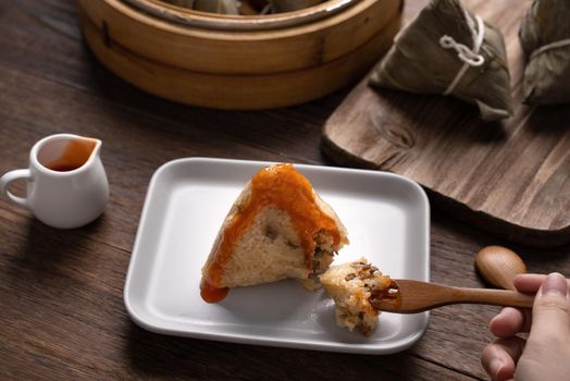 Eating Zongzi rice dumpling for Chinese traditional Dragon Boat Festival (Duanwu Festival) celebration event concept.