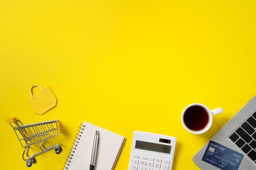 Top view of online shopping design concept with credit card, note, calculator and computer isolated on office yellow table background.