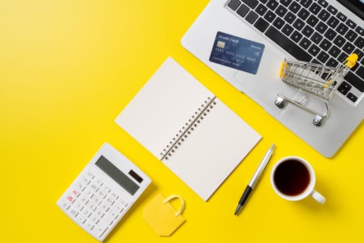 Top view of online shopping design concept with credit card, note, calculator and computer isolated on office yellow table background.