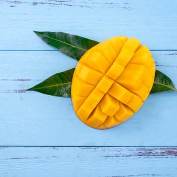 Top view design concept of beautiful mango tropical fruit with sliced chuncks over blue table background.