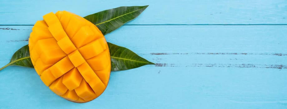 Top view design concept of beautiful mango tropical fruit with sliced chuncks over blue table background.