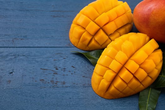 Top view design concept of beautiful mango tropical fruit with sliced chuncks over blue table background.