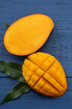 Top view design concept of beautiful mango tropical fruit with sliced chuncks over blue table background.