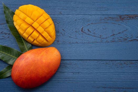 Top view design concept of beautiful mango tropical fruit with sliced chuncks over blue table background.