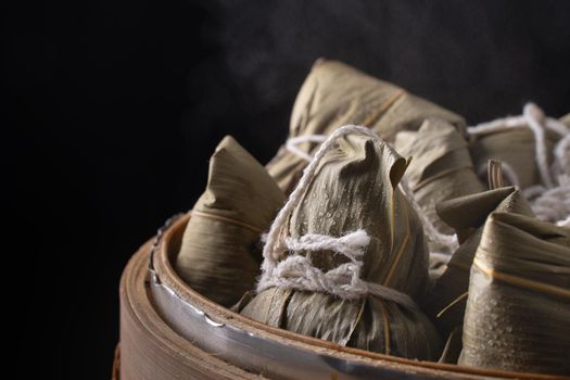 Zongzi rice dumpling for Chinese traditional Dragon Boat Festival (Duanwu Festival) over dark background.