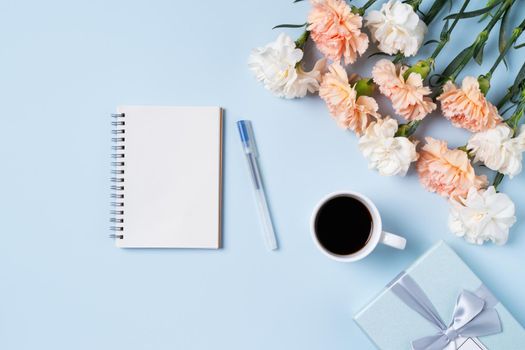 Design concpet of Mother's Day greeting with carnation flower, holiday gift idea and notebook diary on mother's desk background.