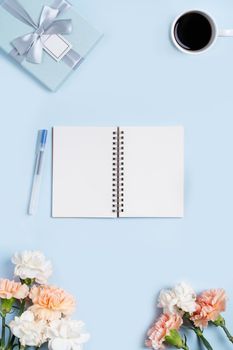 Design concpet of Mother's Day greeting with carnation flower, holiday gift idea and notebook diary on mother's desk background.