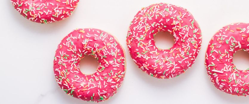 Bakery, branding and cafe concept - Frosted sprinkled donuts, sweet pastry dessert on marble table background, doughnuts as tasty snack, top view food brand flat lay for blog, menu or cookbook design