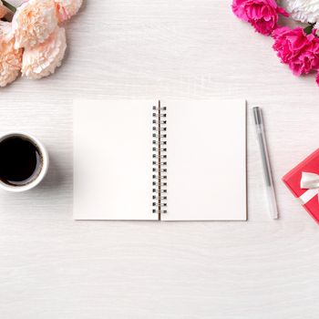 Design concpet of Mother's Day greeting with carnation flower, holiday gift idea and notebook diary on mother's desk background.