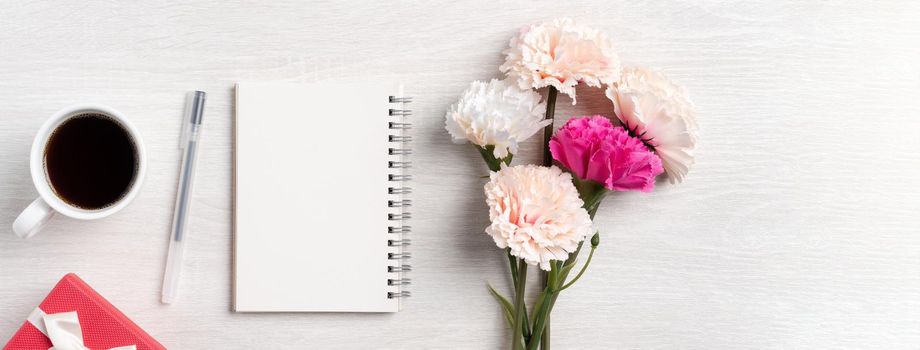 Design concpet of Mother's Day greeting with carnation flower, holiday gift idea and notebook diary on mother's desk background.