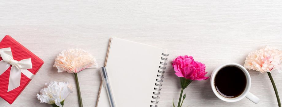 Design concpet of Mother's Day greeting with carnation flower, holiday gift idea and notebook diary on mother's desk background.