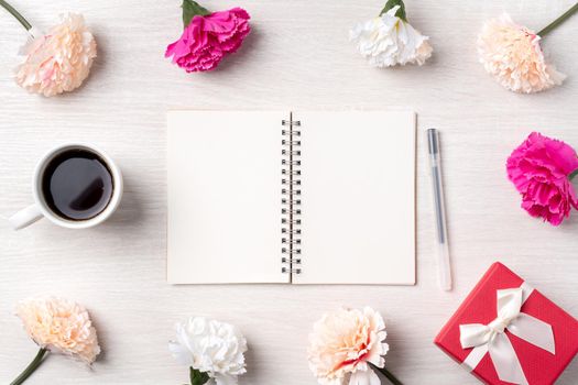 Design concpet of Mother's Day greeting with carnation flower, holiday gift idea and notebook diary on mother's desk background.