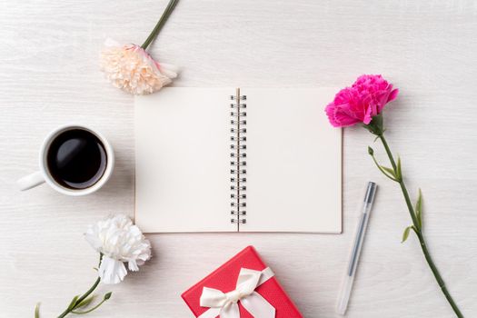 Design concpet of Mother's Day greeting with carnation flower, holiday gift idea and notebook diary on mother's desk background.