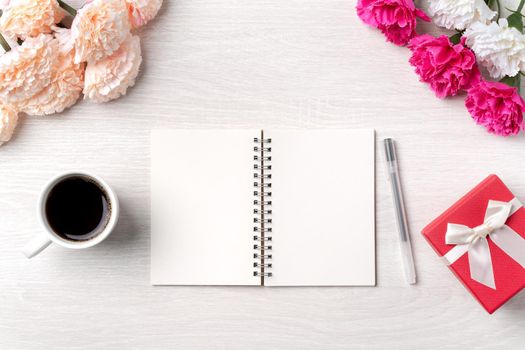 Design concpet of Mother's Day greeting with carnation flower, holiday gift idea and notebook diary on mother's desk background.