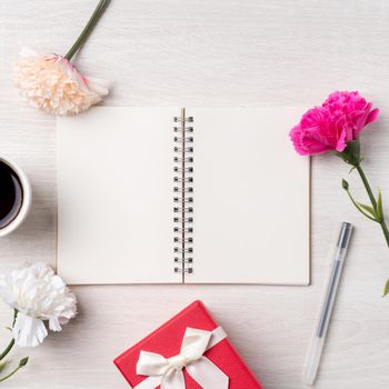 Design concpet of Mother's Day greeting with carnation flower, holiday gift idea and notebook diary on mother's desk background.