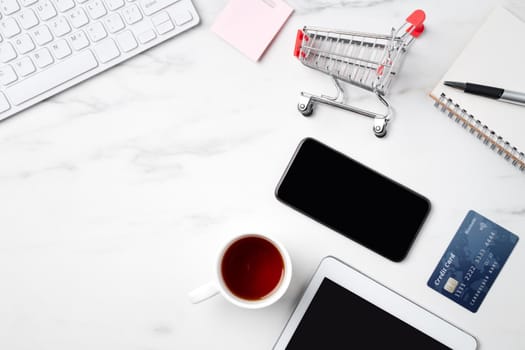 Top view of online shopping concept with credit card and electronics isolated on office marble white table background.